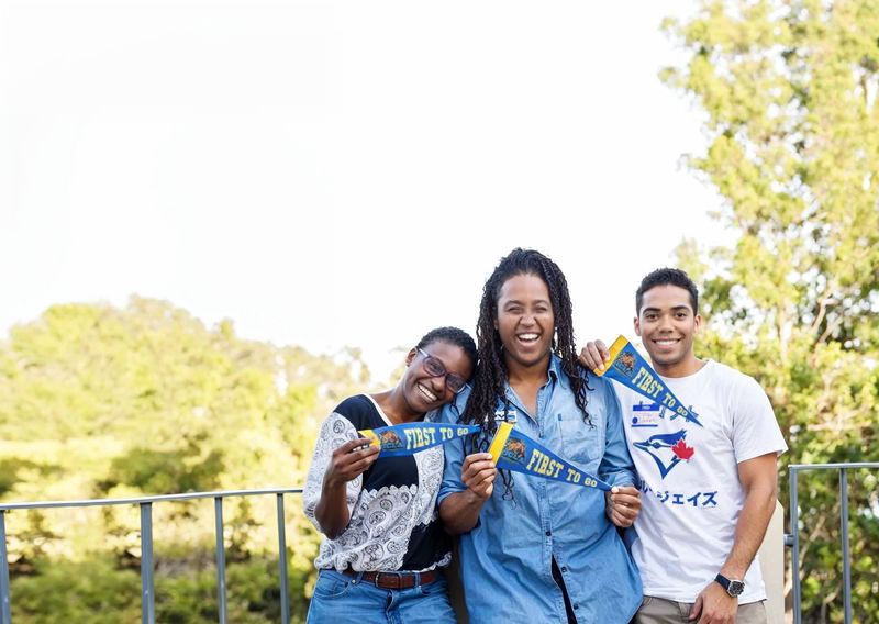 Three people holding UCLA First to Go pennants